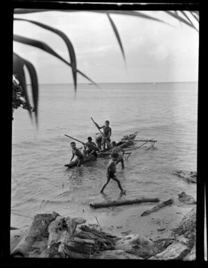 Beach scene including children in small fishing canoe (Paopao or Va'a alo), Samoa