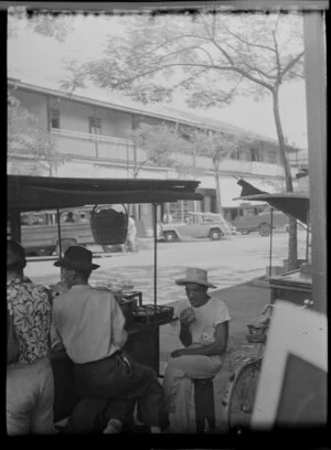 Street scene with people sitting next to vendors cart, Papeete, Tahiti