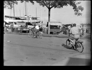 Street scene with two men riding their bicycles, cart stall selling goods, Papeete, Tahiti