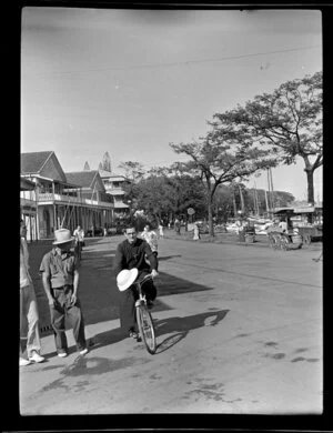 Street scene with men watching priest riding his bicycle, Papeete, Tahiti