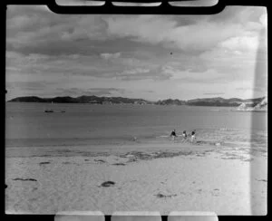 Beach scene at Paihia, Bay of Islands, showing boat and people walking on the beach