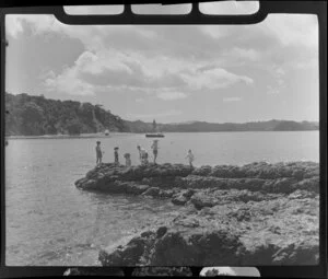 Man and children fishing on a rock at Paihia, Bay of Islands, Northland