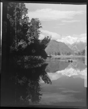 Woman and child in dinghy on Lake Matheson, with reflection of Fox Glacier, West Coast