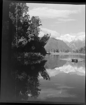 Woman and child in dinghy on Lake Matheson, with reflection of Fox Glacier, West Coast