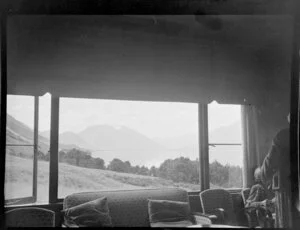 Interior view in the lounge of a lodge looking out towards Lake Ohau, Waitaki District, Canterbury Region, also showing mountains through the windows