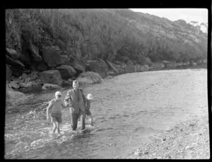 Gillespies Beach, South Westland, showing man and two boys walking through a river