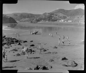 Beach at Piha, Auckland, showing people and a dinghy on a trailor