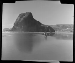 Beach at Piha, Auckland, showing Lion Rock and people walking along beach