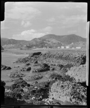 Beach at Piha, Auckland, showing people near small rocks