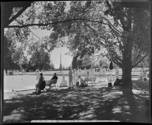 Government Gardens, Rotorua, showing a group of lawn bowls players under trees in front of The Bath House (later known as Rotorua Museum)