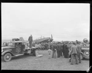 Crowd observing Grumman Avenger converted for aerial topdressing test, Federal flatbed truck delivering superphosphate fertiliser, Masterton