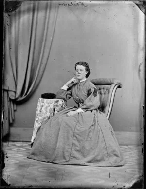 Mrs Neilson, seated, wearing wedding ring and full length frock with belt, lace cuffs and collar