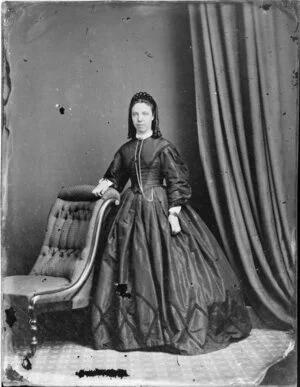 Unidentified woman with hair ornament and ringlets, wearing a shaped bodice over a full skirt with a pattern at the hem