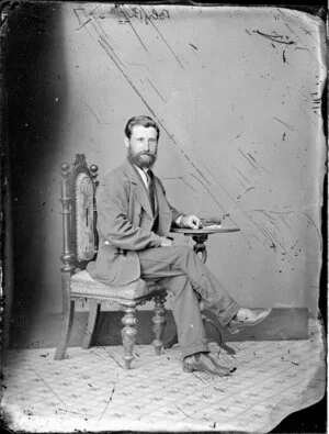 Mr Blyth, sitting with his hand resting on a small table