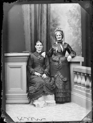Two unidentified women of the Keen family, the older,in a bonnet, standing, and the younger sitting, both in long skirts with underskirts