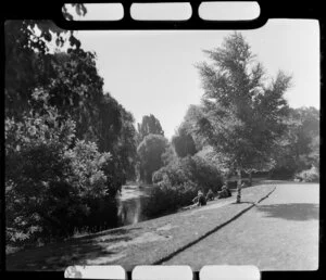 Unidentified group of people sitting alongside Avon River, Christchurch