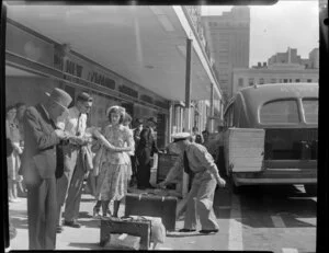 Passengers outside New Zealand National Airways Corporation building waiting to board bus
