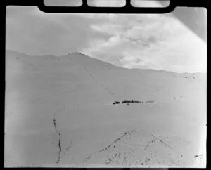 Distant view of chalet and skiers skiing on Coronet Peak, Otago