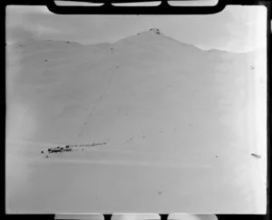 Distant view of chalet and skiers skiing on Coronet Peak, Otago