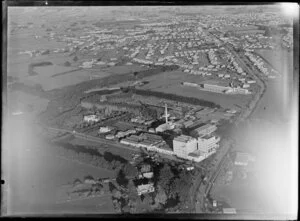 View of Dominion Breweries (previously Waitemata Breweries) bottling plant on the corner of Great South Road and Bairds Road, Otahuhu, Auckland, with college, residential housing and farmland beyond