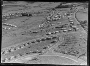 View of new housing development Glen Innes, Auckland City, showing new houses under construction and vacant sites, with established residential area and farmland beyond