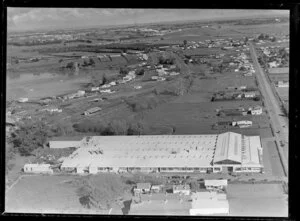 View of Alex Harvey Factory Panmure, Auckland City, with railway line and station, Ireland Road next to Panmure Basin with residential housing and Mount Wellington Highway, looking towards farmland and the inner harbour estuary beyond