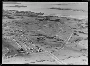 View of housing development Glendowie, Auckland City, with new roads over farmland beyond residential houses and what will become Tahuna Torea Nature Reserve, Kerridge family home in the distance with Churchill Park, tidal estuary, Browns Island, Motuihe Island and Bucklands Beach beyond