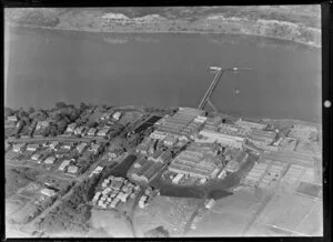 Close-up view over the New Zealand Refrigerating Company, Imlay Freezing Works Imlay Place, Wanganui, with stock pens and yards, and effluent treatment ponds, and stacks of timber next to residential housing with Balgownie Avenue and Wordsworth Street, located beside the Wanganui River with wharf for loading ships