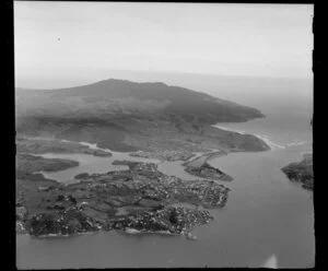 View over Raglan Township on headland, with Raglan Harbour Mouth, Waikato District, showing airport and Wainui Stream with bridge and inner Raglan Estuary to farmland and Mount Karioi National Forest and Tasman Sea beyond