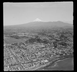 View over New Plymouth waterfront, Taranaki District, with residential housing, racecourse with Eliot Street and Glover Street, back to farmland with Mount Taranaki beyond