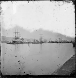 Queens Wharf, Lambton, Wellington, showing several sailing ships docked at wharf and Oriental Bay in distance