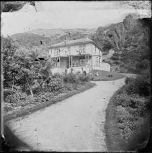 Large two-storied wooden house, possibly in Thorndon, Wellington, with unidentified persons standing on verandah and lawn