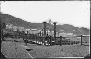 Hobson Street, Thorndon, Wellington, featuring swing bridge with unidentified persons, including road gang at far end, and houses on Tinakori Road