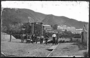 Unidentified group next to swing bridge, Hobson Street, Thorndon, Wellington, including houses on Tinakori Road in background