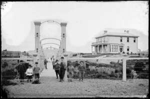 Group of unidentified boys on swing bridge, Hobson Street, Thorndon, Wellington, showing a large two-storied wooden house