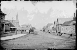 View from Pipitea Street of Mulgrave Street, Thorndon, Wellington, showing buildings on both sides of street and children sitting on footpath