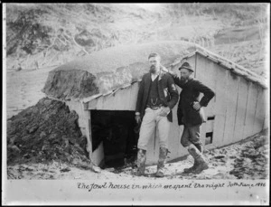 H. Lundis (left) and John Cunningham Blythe standing outside fowl house where they had taken shelter from the eruption of Mount Tarawera