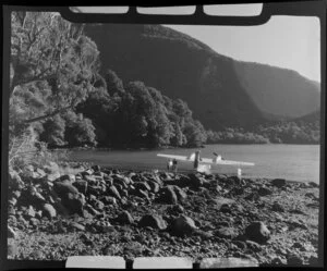 Two unidentified men standing next to an Amphibian Airways aircaft at George Sound, Fiordland National Park, Southland