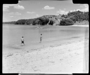 Beach scene, including children playing and two men in rowboat net fishing, Mita's Island, Bay of Islands, Northland
