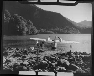 A group of unidentified men next to an Amphibian Airways aircraft at George Sound, Fiordland National Park, Southland