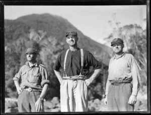 Amphibian Airways, George Sound, Fiordland, view of 3 hunters on rocky shore, mountains behind