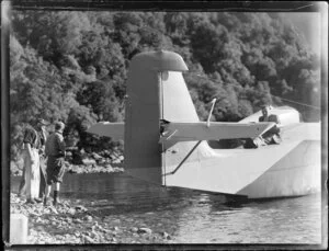 Amphibian Airways, George Sound, Fiordland, view of hunters on rocky shore looking at man sitting on flying boat