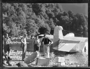 Amphibian Airways, George Sound, Fiordland, view of hunters on rocky shore with provisions, flying boat behind