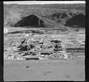 Kawerau, Bay of Plenty, showing a close-up view of Tasman Pulp and Paper Mill under construction, with bush covered hills beyond