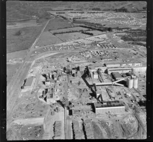Kawerau, Bay of Plenty, showing a close-up view of Tasman Pulp and Paper Mill under construction, with new housing estate and Lake Pupwharau beyond