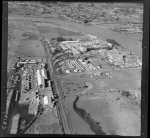Whakatane Board Mills, Whakatane, Bay of Plenty, showing wood pulp processing plant besides Whakatane River and Mill Road with timber processing yard, with the Whakatane River and residential housing beyond