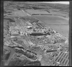 Kawerau, Bay of Plenty, showing Tasman Pulp and Paper Mill under construction with workers housing to Tamarangi Drive (State Highway 34) with farmland beyond
