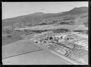 Kawerau, Bay of Plenty, showing Tasman Pulp and Paper Mill under construction with Tamarangi Drive (State Highway 34), with housing subdvision and hills beyond