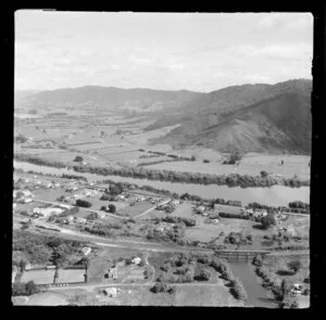 Taupiri, Waikato, view of township on the banks of the Waikato River and Great South Road (State Highway 1), railway station and rail bridge over the Mangawara Stream, lawn bowls and tennis courts, farmland beyond