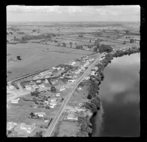 Taupiri, Waikato, view of township on the banks of the Waikato River with the Great South Road (State Highway 1) and Te Putu Street, residential housing and railway, with farmland beyond